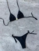 Conjunto de bikini color crema con corpiño triangular con detalle de estrella dorada y bombacha con tiras laterales.