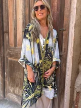 Kimono de seda con mangas anchas y estampado de motivos naturales en tonos negro, amarillo mostaza y gris claro. Presenta un ribete decorativo en el frente.