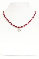Collar corto con cuentas cilíndricas rojas y blancas alternadas, y dije colgante en forma de estrella de nácar con borde dorado.