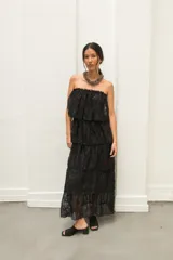 Vestido largo de encaje negro, strapless y con volados en capas.