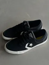 Championes Converse C All Star de lona negra con suela blanca, cordones negros y el logo de la estrella y el chevron en blanco en el lateral.