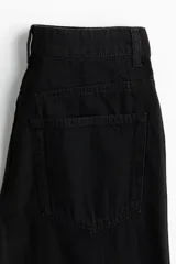 Pantalón de jean negro de corte ancho, tiro alto y largo cropped.