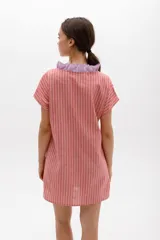 Vestido corto con rayas verticales y horizontales en tonos grises y blancos, con volados color lima en el escote y cierre frontal con botones.