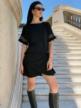 Remera negra de corte holgado con mangas cortas con volados y detalle de apliques de piedras en los volados.