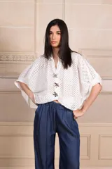 Camisa blanca calada con botones y mangas cortas. Incluye tres prendedores con forma de flor.