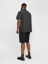 Short chino negro de lino y algodón, corte relajado, cintura media con elástico y cordón ajustable, bolsillos frontales y traseros.