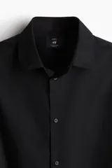 Camisa negra de manga larga con cuello italiano y tapeta lisa. Presenta un corte ajustado (slim fit) y bajo redondeado.