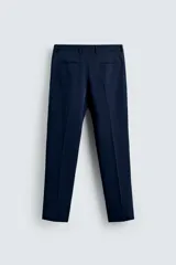 Pantalón de vestir azul marino, de corte slim fit, con bolsillos laterales y traseros. Se ajusta a la cintura con cinturón de cuero marrón.
