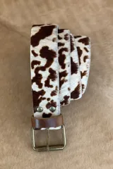 Cinturón de cuero con estampado animal print blanco y negro, hebilla metálica plateada y pasador de cuero negro.