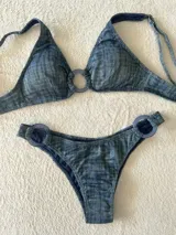 Conjunto de bikini turquesa con textura acanalada, compuesto por un corpiño triangular con argolla central y una bombacha vedetina con argollas en los laterales.