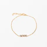 Pulsera dorada de cadena fina con cuatro cristales engarzados.