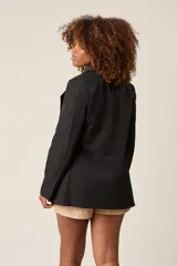 Blazer negro de corte sastre, con solapas de muesca, cierre frontal con un botón y bolsillos delanteros con solapa.