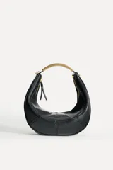 Bolso negro de formato ovalado con asa metálica dorada. Tiene detalle de pespunte en contraste en el cuerpo, bolsillo interior con cremallera y cierre mediante cremallera y tirador.
