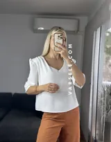 Blusa negra de crepé de lino con escote en V, mangas 3/4 con hombreras y detalle fruncido en los hombros. Se ata en la espalda con tiritas.