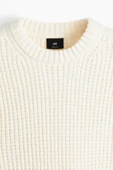 Buzo de punto texturizado suave de chenille, color crema, con cuello redondo ribeteado, hombros caídos y puños y bajo en punto acanalado.