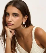 Aros dorados con base de resina blanca y colgante circular.