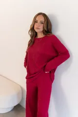Conjunto de buzo y pantalón texturizado color fucsia. El buzo es de corte holgado y cuello redondo. El pantalón es de corte recto y tiro alto.