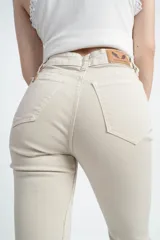 Pantalón acampanado color beige, de tiro alto y corte ajustado en la cadera.
