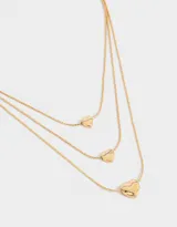 Collar dorado multicadena con tres cadenas de diferentes largos, cada una con un dije de corazón.