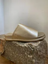Sandalias bajas doradas con capellada y plantilla de cuero y suela de caucho.