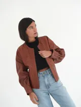 Campera oversize de cuero color marrón con cierre frontal y detalles de costuras en los bordes.