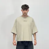 Remera verde militar de corte cuadrado con estampado en la espalda que incluye un globo terráqueo y la frase "Built to Break Limits".