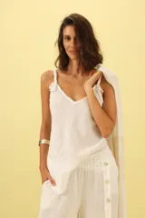 Musculosa blanca de lino con breteles trenzados y detalle de flecos en el escote.