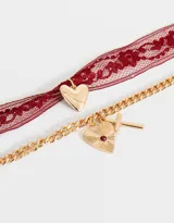 Set de dos collares cortos: uno con cinta de encaje color borgoña y dije de corazón dorado; otro con cadena dorada y dijes de corazón con textura y cruz con detalle de cristal rojo.