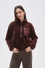 Buzo de polar tipo 'teddy' color bordó, con cuello alto y cierre frontal parcial. Cuenta con un bolsillo de parche con cierre en el pecho confeccionado en tela técnica a tono, mangas largas y calce holgado.