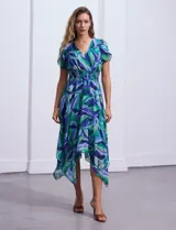 Vestido midi de gasa estampada con motivos florales en tonos azules y verdes. Escote en V tanto en la parte delantera como en la espalda. Corte en la cintura con punto smock y ruedo asimétrico.
