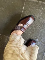 Sandalias de cuero marrón con diseño abierto y hebilla lateral ajustable.