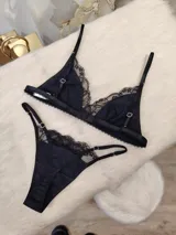 Conjunto de lencería negro, compuesto por un corpiño triangular de algodón con detalles de encaje y una tanga de algodón con detalles de encaje.