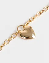 Collar corto dorado con cadena de eslabones gruesos y dije de corazón inflado.