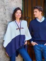 Ruana bicolor en crudo y azul marino, con cierre frontal de hebilla de cuero marrón.