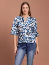 Blusa blanca de gasa marca Sioni, con cuello a la base y escote en V. Tiene abertura central con botones y mangas 3/4 con terminación fruncida.