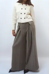 Chaqueta color crudo de tejido de punto con cuello solapa y manga larga. Tiene bolsillos de parche delanteros y cierre cruzado con doble botonadura.