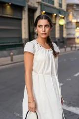 Vestido midi blanco de corte recto con escote redondeado y detalle de frunces. Tiene lazo en la cintura para ajustar la silueta y mangas cortas.