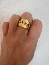 Anillo dorado regulable con forma irregular y piedras de colores.