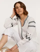 Blusa blanca de manga larga con bordados negros en cuello, mangas y frente.