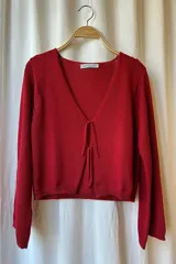 Blusa corta de punto color rojo, con escote en V y cierre frontal con lazos. Tejido artesanal en hilado 70% algodón y 30% acrílico.