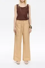 Pantalón corte jogger color beige con largo tobillero, bolsillos tipo alforja, cintura elástica ajustable con cordones y logo bordado.