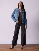 Campera de jean celeste de la marca Baccini, con cierre central, bolsillos delanteros, apliques colgantes de tachas en los hombros y terminación desflecada en el ruedo.