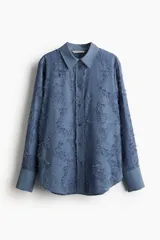 Camisa celeste con textura, cuello clásico, abotonada al frente, mangas largas con puños abotonados y bajo redondeado.
