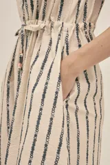 Vestido camisero color crema con rayas verticales negras y estampado floral, confeccionado en tejido seersucker de algodón con botones nacarados y lazo para ajustar la cintura.