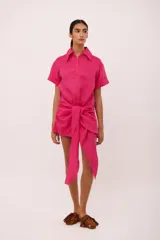 Vestido corto fucsia con cuello camisero, mangas cortas y lazo en la cintura.