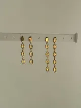 Par de caravanas colgantes doradas con forma de granos de café.