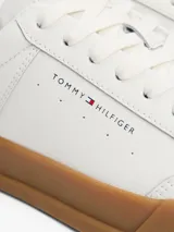 Zapatillas Tommy Hilfiger blancas de cuero, con suela marrón y detalle azul en el talón.