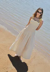 Vestido largo color crema con rayas verticales finas, fruncido en el busto y falda globo. Tiene detalles tejidos de crochet en breteles y escote.