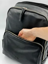 Mochila negra de cuero vacuno con cierres dorados. Tiene dos compartimentos principales con cierre y un compartimento interno acolchado para laptop.