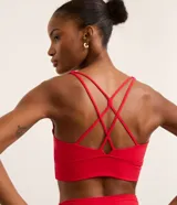 Top deportivo alargado color rojo, confeccionado en microfibra con escote en U, tiras finas cruzadas en la espalda y cintura ancha. Incluye copas removibles.